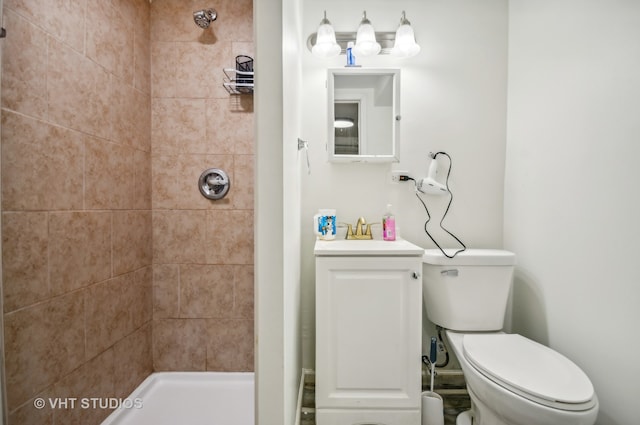 bathroom with a tile shower, toilet, and sink