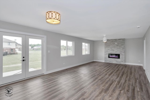 unfurnished living room featuring a wealth of natural light, dark hardwood / wood-style floors, a large fireplace, and french doors