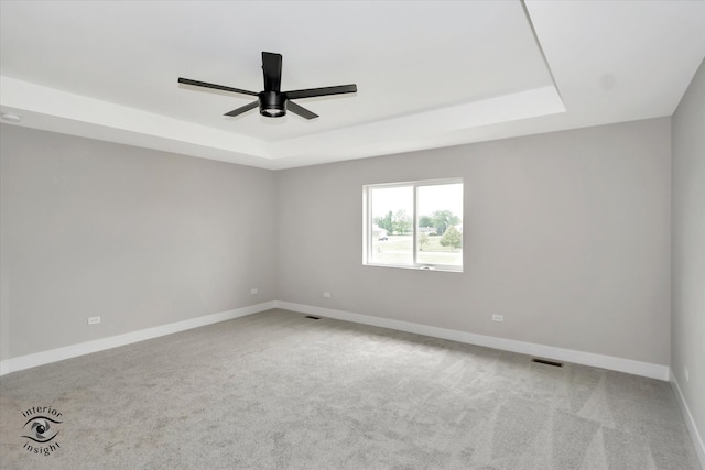 empty room featuring carpet flooring, ceiling fan, and a tray ceiling