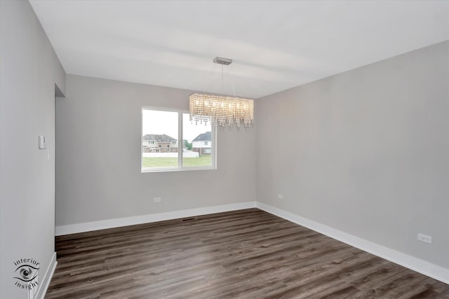 spare room featuring an inviting chandelier and dark hardwood / wood-style flooring