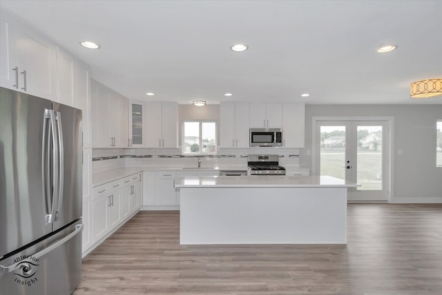 kitchen featuring white cabinetry, tasteful backsplash, light hardwood / wood-style flooring, and stainless steel appliances