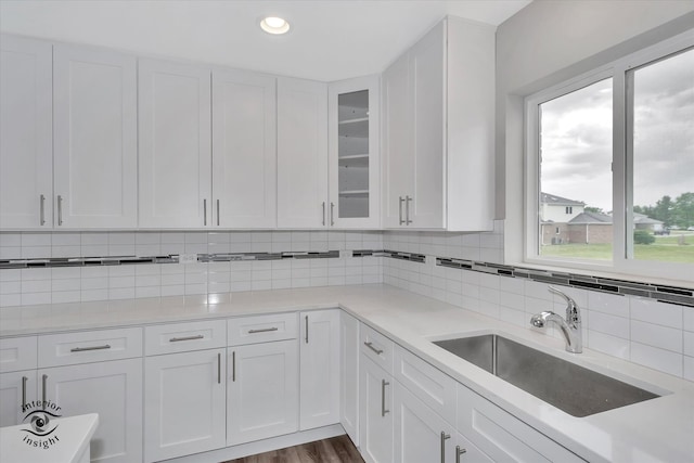 kitchen with backsplash, hardwood / wood-style floors, white cabinetry, and sink