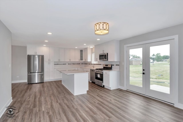 kitchen featuring a healthy amount of sunlight, wood-type flooring, white cabinets, and appliances with stainless steel finishes