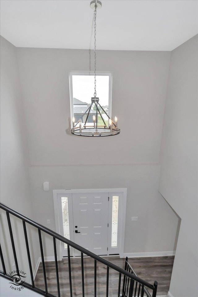 entrance foyer with plenty of natural light, stairs, a chandelier, and wood finished floors