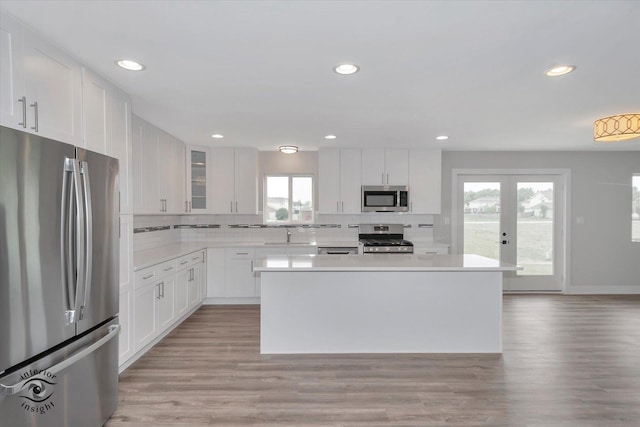 kitchen featuring light wood-type flooring, tasteful backsplash, stainless steel appliances, and a center island