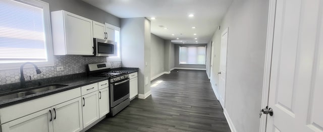 kitchen with stainless steel appliances, light hardwood / wood-style floors, white cabinets, and dark stone countertops