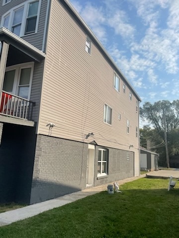 view of home's exterior featuring a yard and a balcony