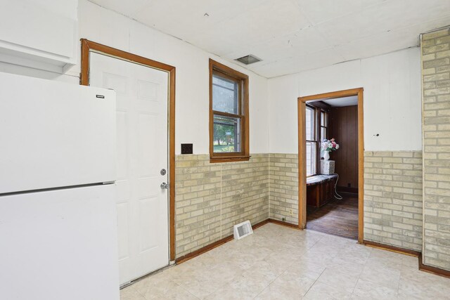 hallway with brick wall and light tile patterned floors