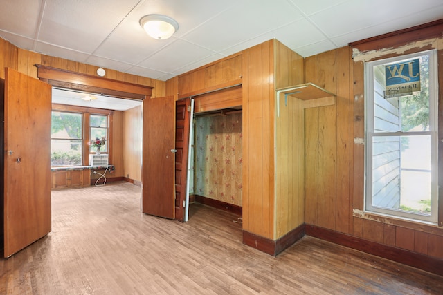 interior space with wood walls, hardwood / wood-style flooring, and a drop ceiling