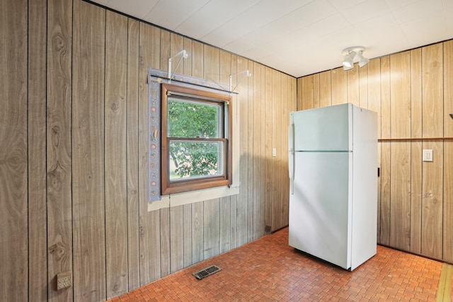 interior space with wood walls, white fridge, and tile patterned floors