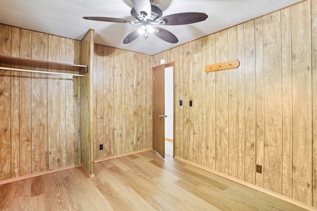 spare room with wood walls, light hardwood / wood-style flooring, and ceiling fan