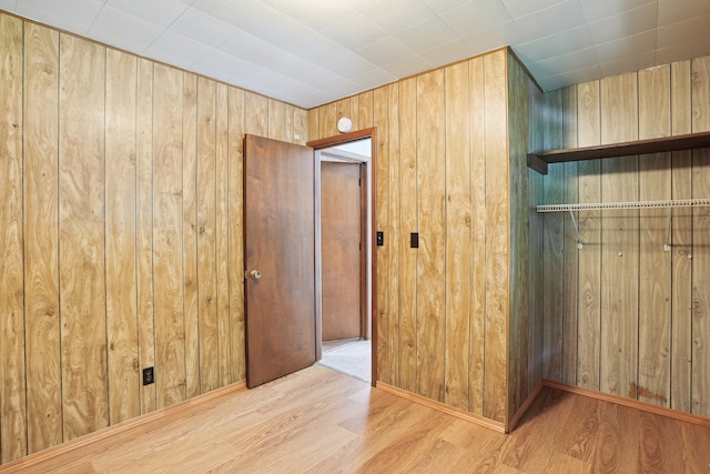 spare room featuring wood walls and light hardwood / wood-style flooring