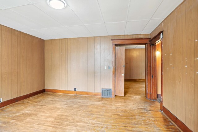 empty room with light hardwood / wood-style floors and wooden walls