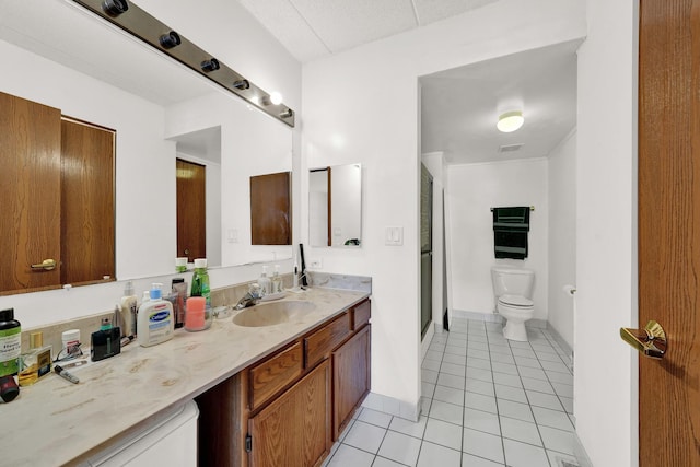 bathroom featuring tile patterned floors, toilet, a shower with shower door, and vanity