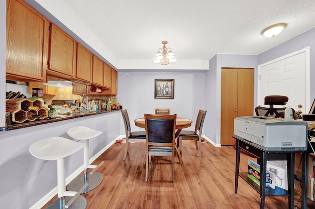 dining space with sink, light hardwood / wood-style floors, and a chandelier