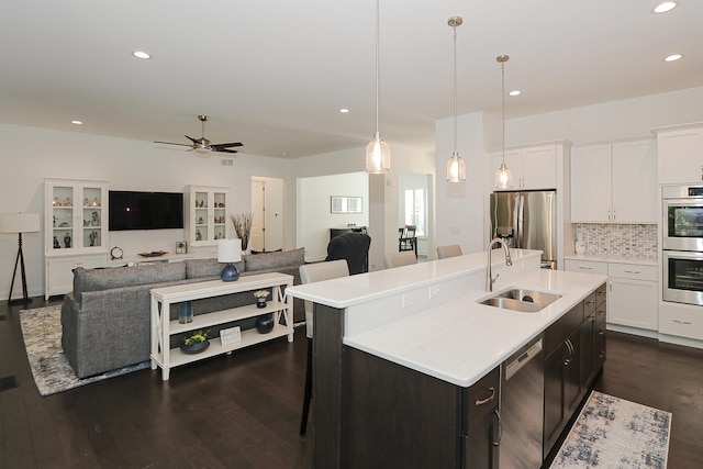 kitchen with ceiling fan, sink, hanging light fixtures, a kitchen island with sink, and appliances with stainless steel finishes