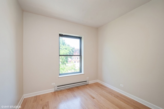 spare room featuring light wood-type flooring and a baseboard heating unit