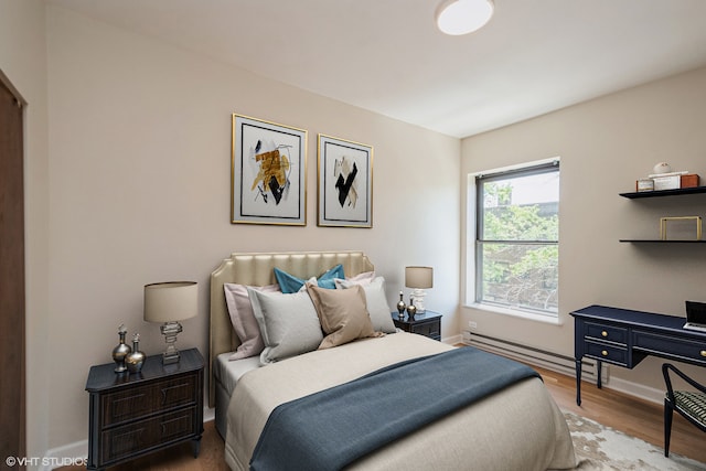 bedroom featuring light hardwood / wood-style floors and a baseboard heating unit