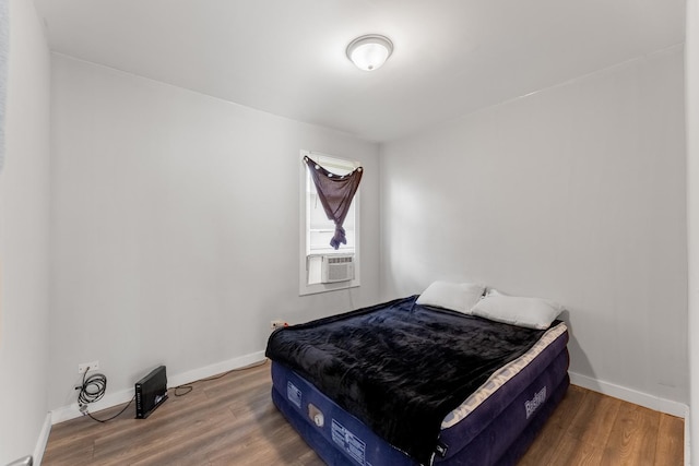 bedroom featuring cooling unit, baseboards, and wood finished floors