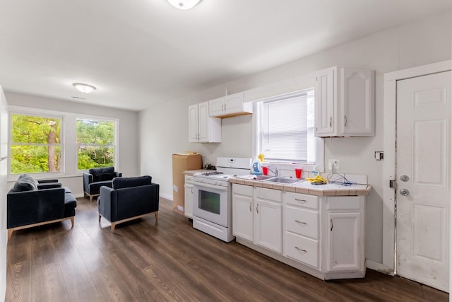 kitchen with dark wood-style flooring, tile countertops, open floor plan, white cabinets, and white gas range oven