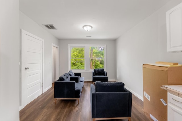 living area with baseboards, visible vents, and dark wood finished floors