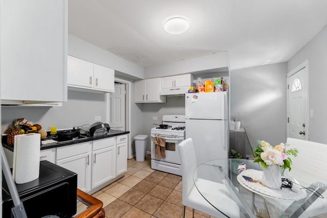 kitchen with light tile patterned flooring, under cabinet range hood, white appliances, white cabinets, and dark countertops