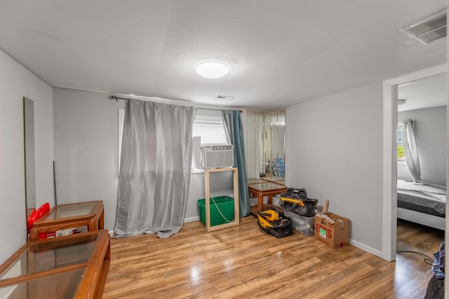 interior space with light wood-type flooring, baseboards, visible vents, and cooling unit