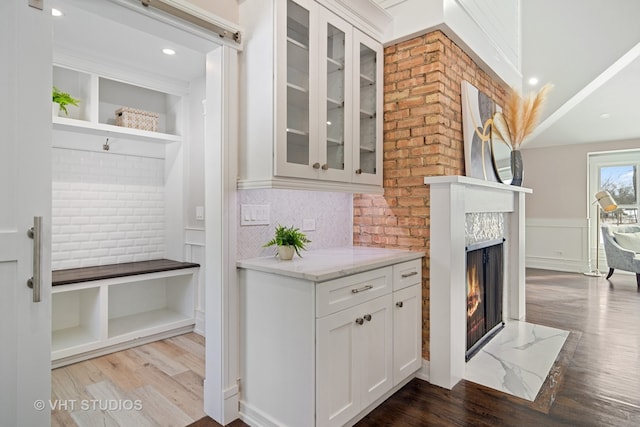 interior space with white cabinets, light hardwood / wood-style flooring, light stone countertops, and a high end fireplace