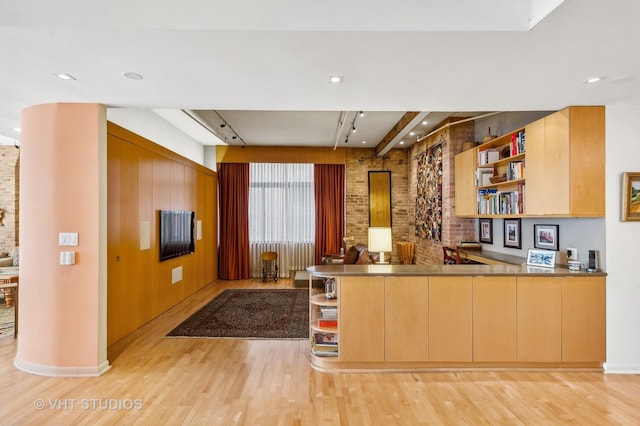 kitchen with light brown cabinetry, light hardwood / wood-style floors, and kitchen peninsula