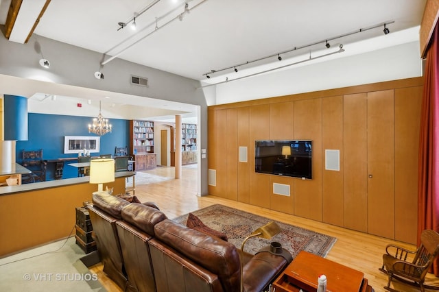 living room with decorative columns, track lighting, a notable chandelier, and light hardwood / wood-style flooring