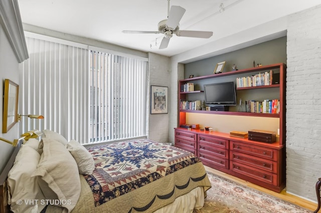 bedroom featuring ceiling fan and brick wall