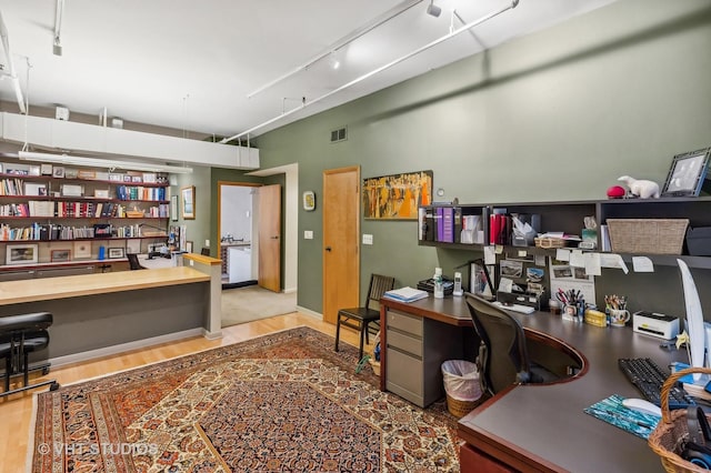 home office featuring built in desk, track lighting, and light wood-type flooring