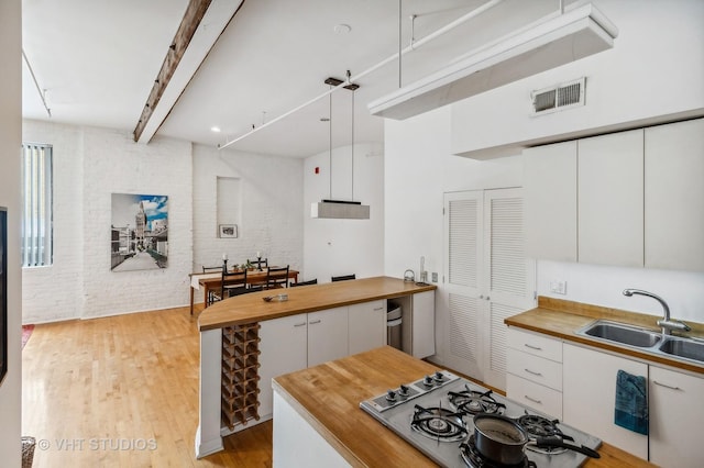 kitchen with brick wall, sink, white cabinets, and white gas cooktop