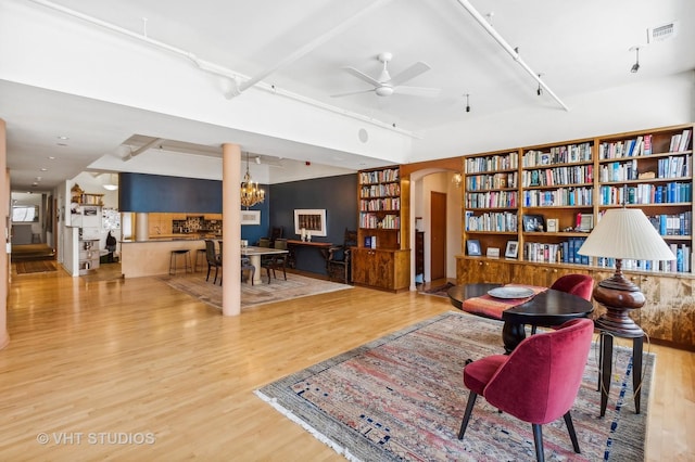 living room featuring ceiling fan with notable chandelier, built in shelves, and hardwood / wood-style floors