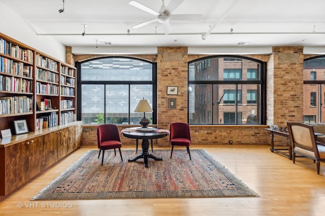 sitting room with light hardwood / wood-style flooring, ceiling fan, and brick wall