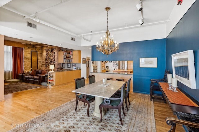 dining room featuring hardwood / wood-style floors, track lighting, and an inviting chandelier