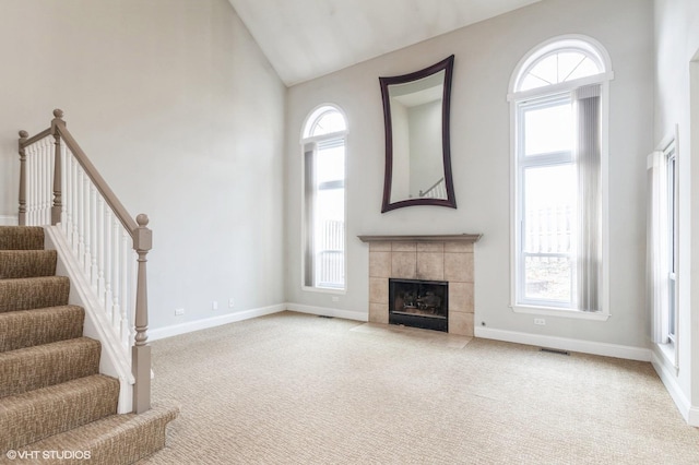 unfurnished living room with a tile fireplace, light carpet, and a wealth of natural light