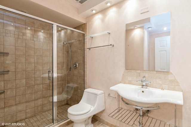 bathroom featuring backsplash, sink, a shower with shower door, and toilet