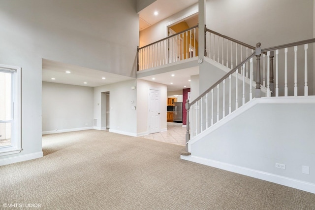 unfurnished living room with light carpet and a towering ceiling