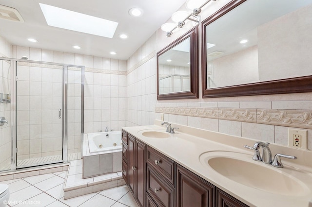 full bathroom with a skylight, tile patterned flooring, vanity, and tile walls