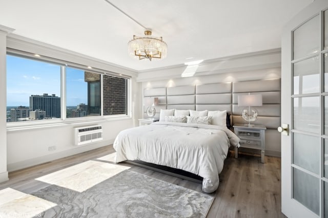 bedroom featuring a notable chandelier, an AC wall unit, and hardwood / wood-style flooring