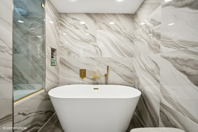 bathroom featuring tile walls and a bath