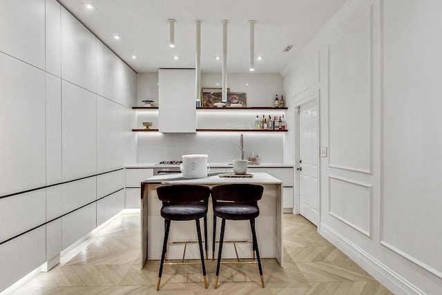 kitchen featuring range hood, light parquet floors, a center island, and white cabinets