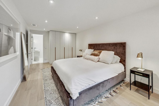 bedroom featuring light hardwood / wood-style flooring and ensuite bathroom