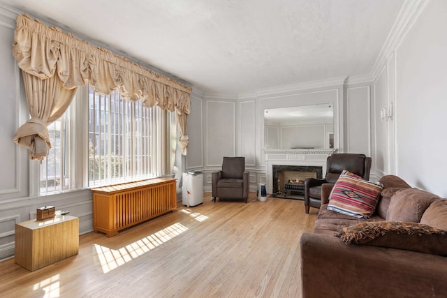 living room with light hardwood / wood-style floors, crown molding, and radiator