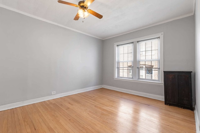 spare room featuring crown molding, radiator, light wood-type flooring, and ceiling fan