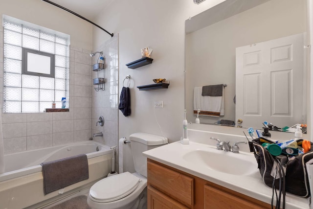 full bathroom with tiled shower / bath combo, a healthy amount of sunlight, toilet, and vanity