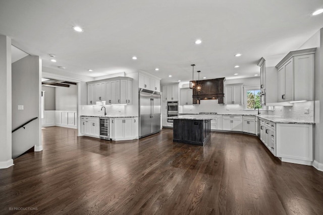 kitchen featuring dark hardwood / wood-style flooring, stainless steel appliances, beverage cooler, a kitchen island, and hanging light fixtures