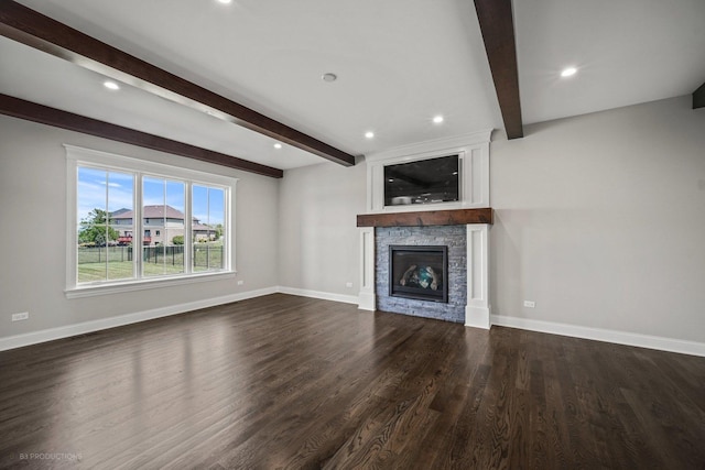 unfurnished living room with beamed ceiling, a stone fireplace, and dark wood-type flooring