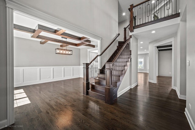 staircase with beam ceiling, an inviting chandelier, coffered ceiling, and wood-type flooring